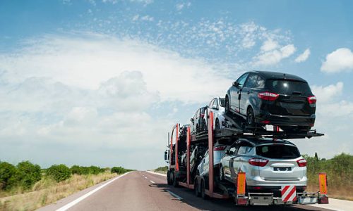 Articulated truck transport of automobiles driving on the road.